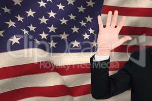 Composite image of businessman in suit with hand raised