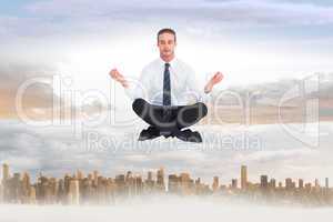 Composite image of businessman meditating in lotus pose