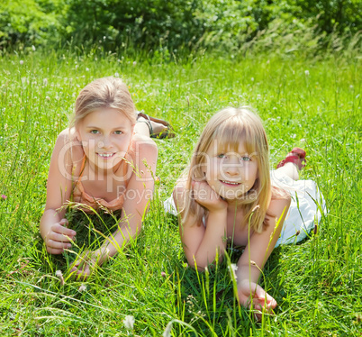 girls lying on green grass