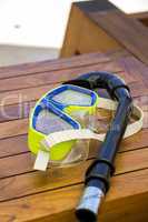 A snorkel and goggles lying on a wooden bench