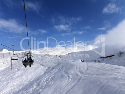 Chair-lift and off-piste slope in wind day