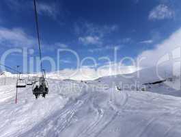 Chair-lift and off-piste slope in wind day
