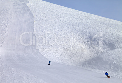 Ski slope and skiers at sun day