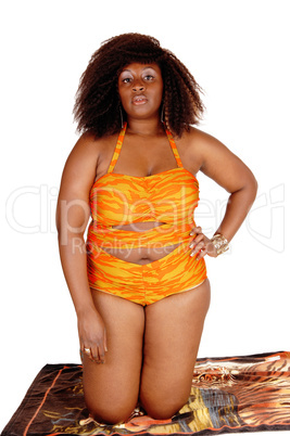 African woman in bikini kneeling.