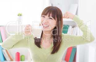Asian female drinking milk and showing strong arm