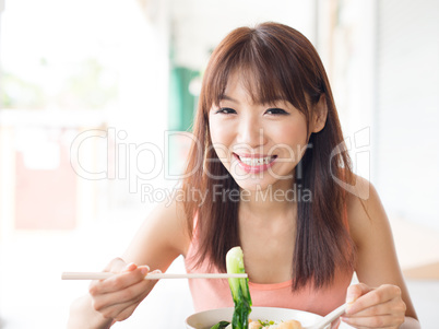 Asian girl eating vegetable noodles