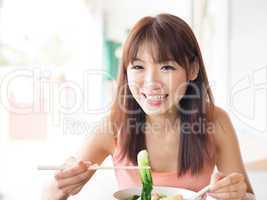 Asian girl eating vegetable noodles