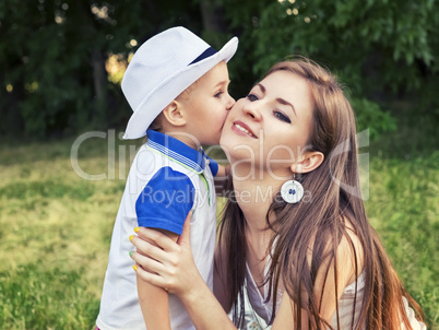 Boy kissing his mother on the cheek outdoors