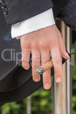 Hand of man in tails holding cigar