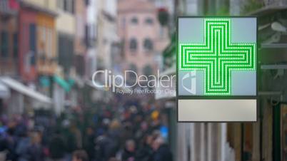 Pharmacy sign with green cross in busy street