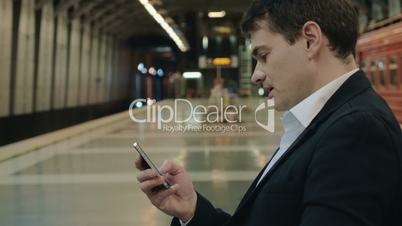 Young handsome businessman texting on cell in subway