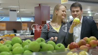 Happy young couple buying apples in the supermarket