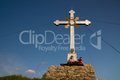 zwei Wanderer an einem Gipfelkreuz