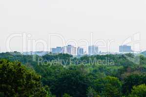 Green forest against distant buildings