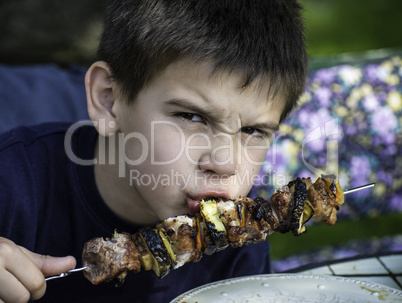 Child eating meat on a skewer