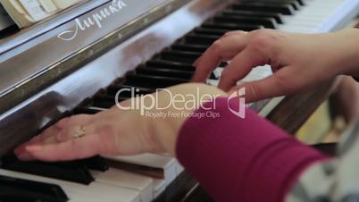 Woman's hands on the keyboard of the piano