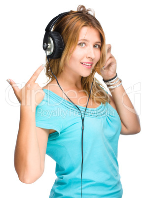 music and technology concept - young woman listening to music and show on her headphones, isolated on white.
