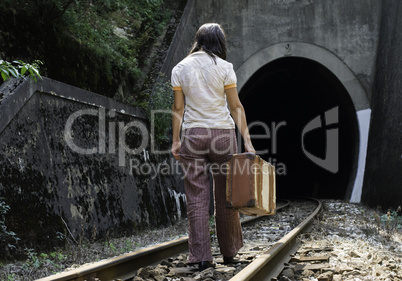 Woman and vintage suitcase on railway road