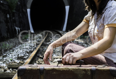 Woman and vintage suitcase on railway road