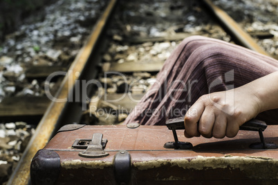 Woman and vintage suitcase on railway road