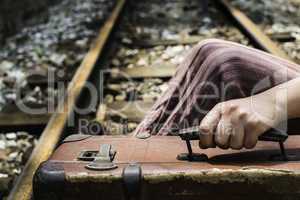 Woman and vintage suitcase on railway road