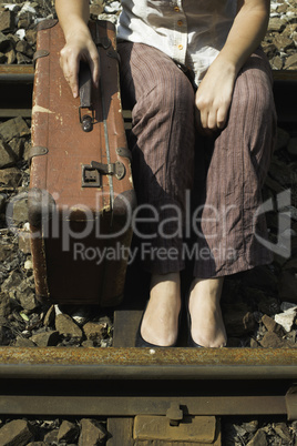 Woman and vintage suitcase on railway road