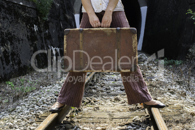 Woman and vintage suitcase on railway road