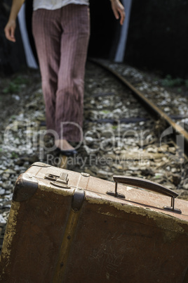 Woman and vintage suitcase on railway road