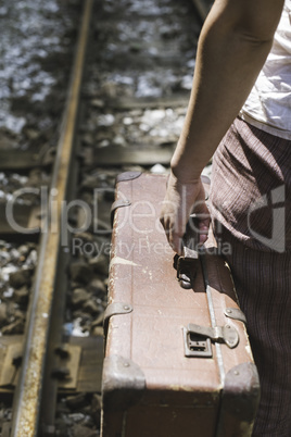 Woman and vintage suitcase on railway road