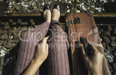 Woman and vintage suitcase on railway road