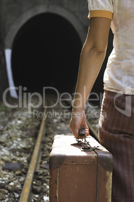 Woman and vintage suitcase on railway road