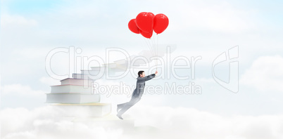 Composite image of businessman flying with balloons