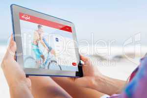 Composite image of woman sitting on beach in deck chair using ta