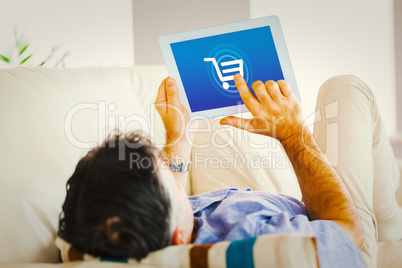 Composite image of man laying on sofa using a tablet pc