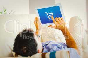 Composite image of man laying on sofa using a tablet pc