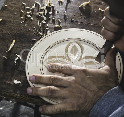 Hands of woodcarver make ??wooden bowl