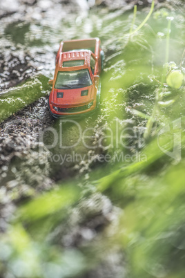 Small red off road car toy in the nature