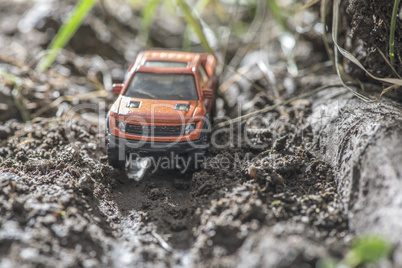 Small red off road car toy in the nature.