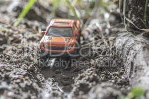 Small red off road car toy in the nature.