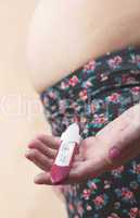 Pregnant woman holding a pregnancy test