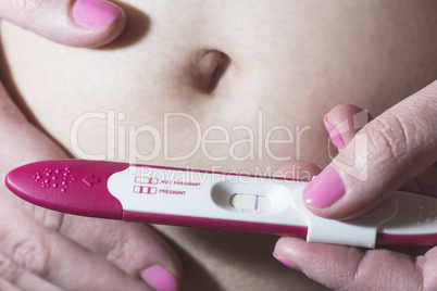 Pregnant woman holding a pregnancy test