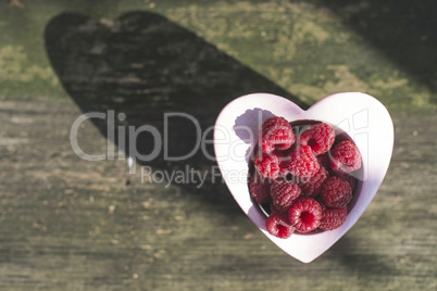 Raspberries in a bowl on wood