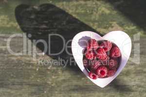 Raspberries in a bowl on wood