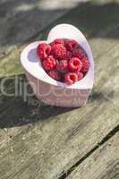 Raspberries in a bowl on wood