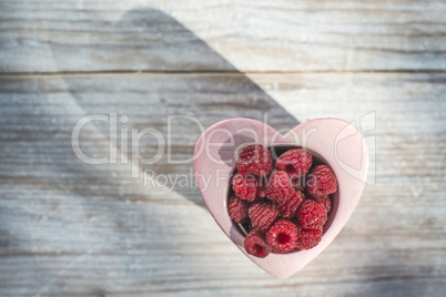 Raspberries in a bowl on wood