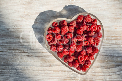 Raspberries in a bowl on wood