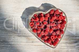 Raspberries in a bowl on wood