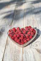 Raspberries in a bowl on wood