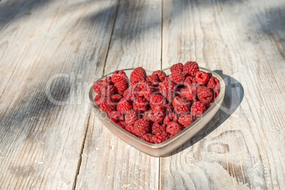 Raspberries in a bowl on wood