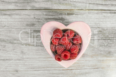 Raspberries in a bowl on wood